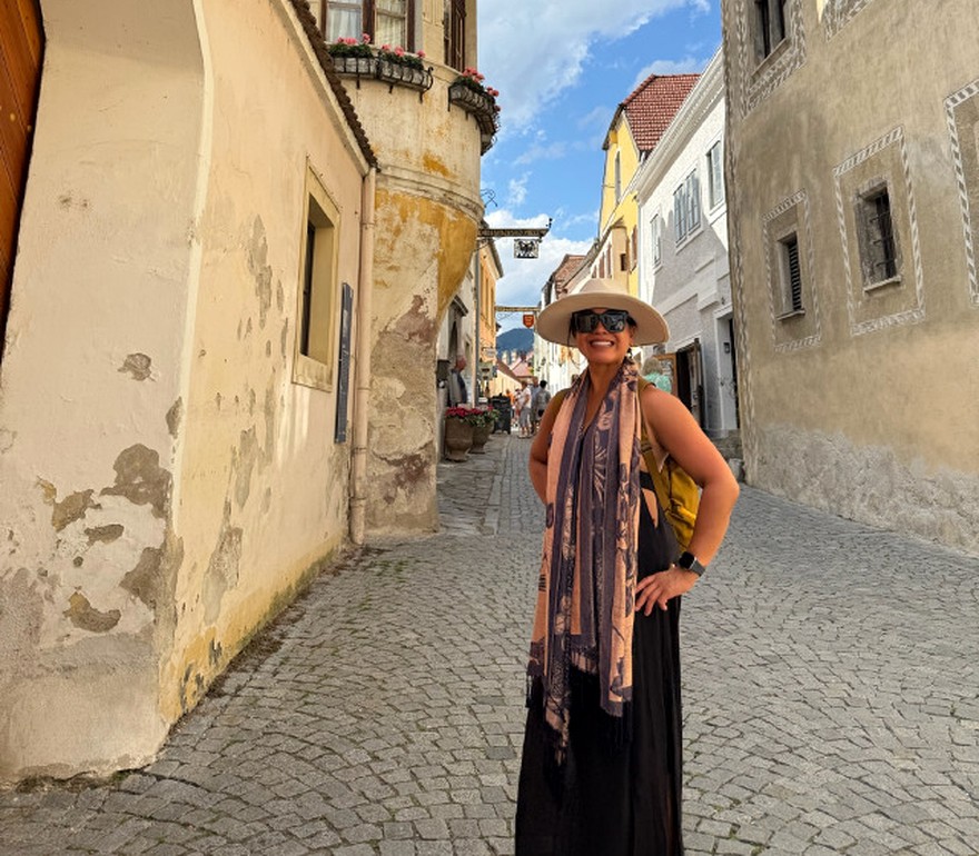 Riza Ayson in a sunlit cobbled lane beside a historic round tower